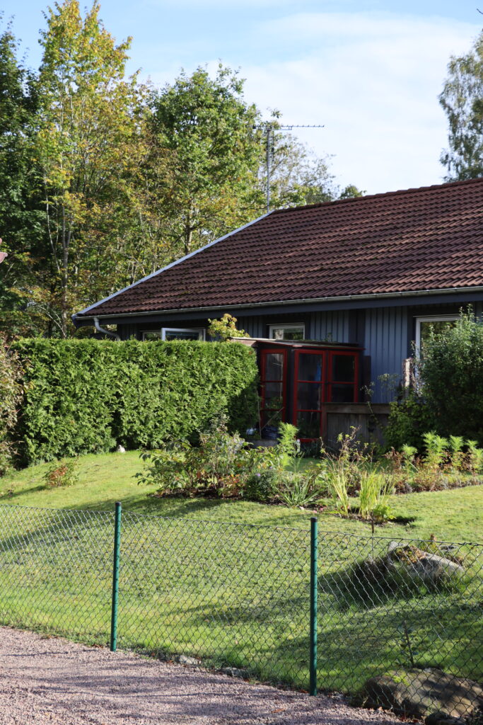 Ljusblå fastighet på Flintavägen i Höör, uppdelat på två trädgårdar med grön häck mellan tomterna.