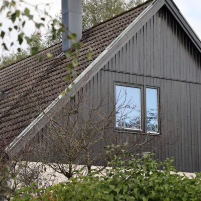 Ovanvåning på hus med svart träfasad och fönster.