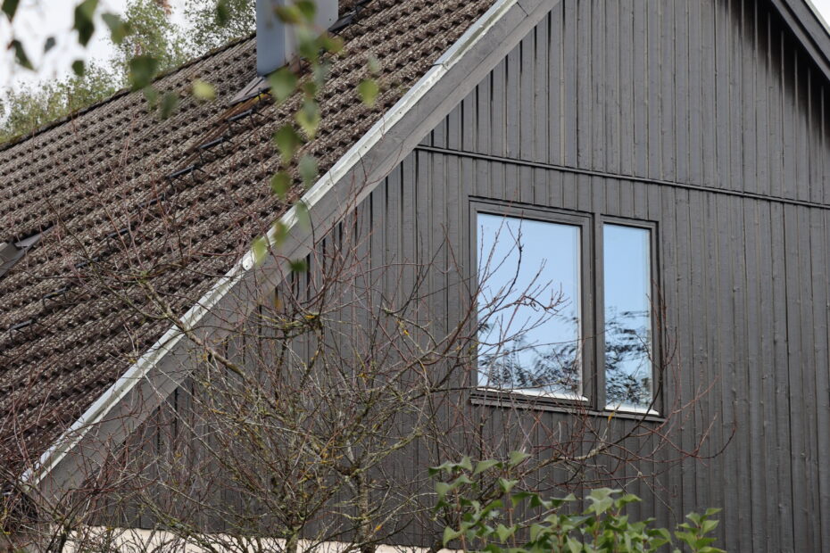 Ovanvåning på hus med svart träfasad och fönster.