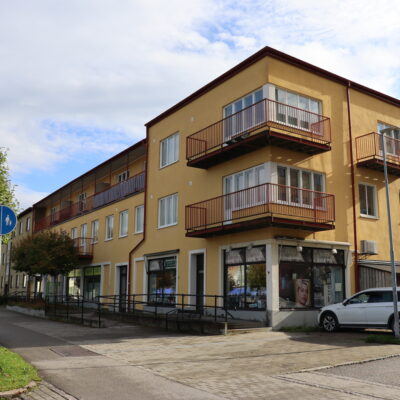 Gul hörnfastighet med röda balkonger på Järnvägsgatan 4 i Höör.