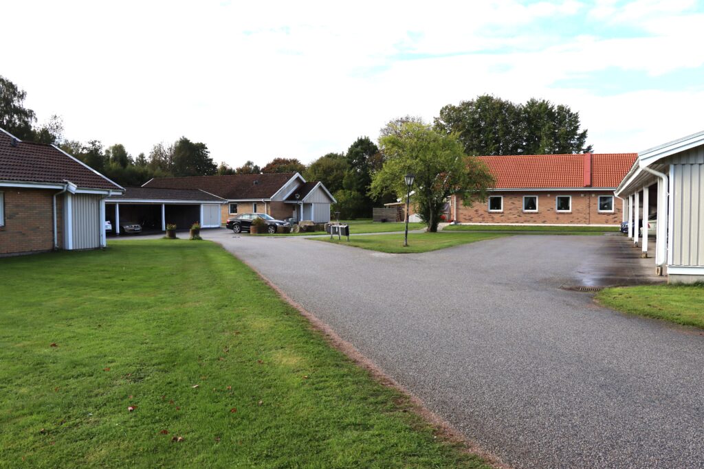 Tre fastigheter i Ludvigsborg med garageportar till höger och ljusbruna tegelhus till vänster