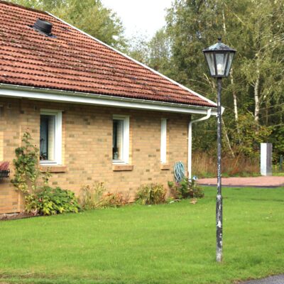 Husknut med ljusbrunt tegel, vita fönster och lyktstolpe på gräsmattan utanför.
