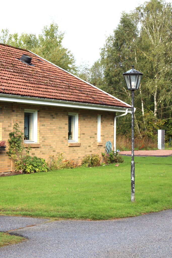 Husknut med ljusbrunt tegel och lyktstolpe i gräsmatta.