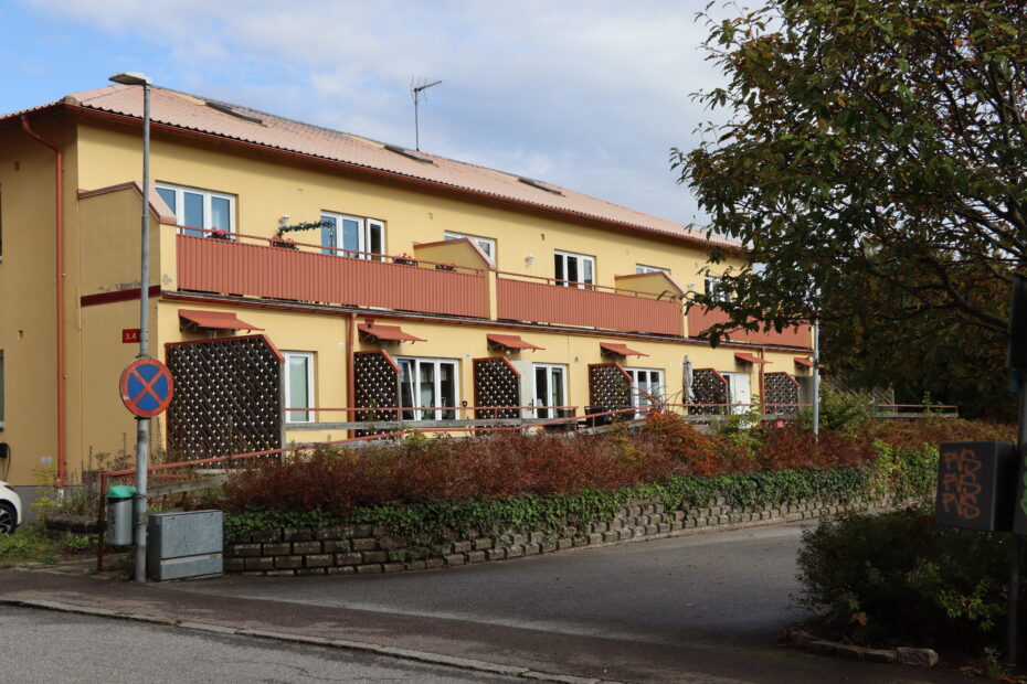 Gul fastighet på Möllebacken 3 i Höör, hyresrätterna är separerade med röd balkong och vägg/insynsskydd.