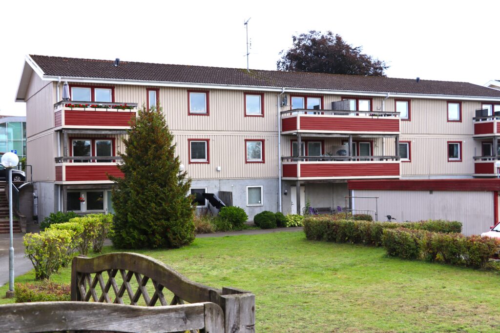 Östergatan/Järnvägsgatan i Höör, ljusgul fastighet med röda balkonger och innergård med gräsmatta.